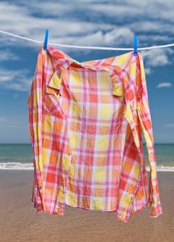 Orange checkered shirt drying on a rope on a tropical beach