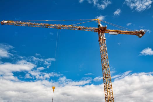 Part of yellow construction tower crane arm against blue sky