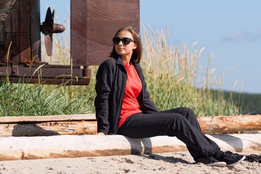 Girl on a deserted beach in the background of an old rusty screws fishing schooner