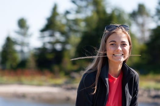 beautiful girl with an ear in his teeth against the backdrop of pine forests. The limited depth of field.