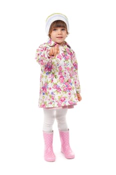 little girl in boots and a jacket shows finger. Isolate on white