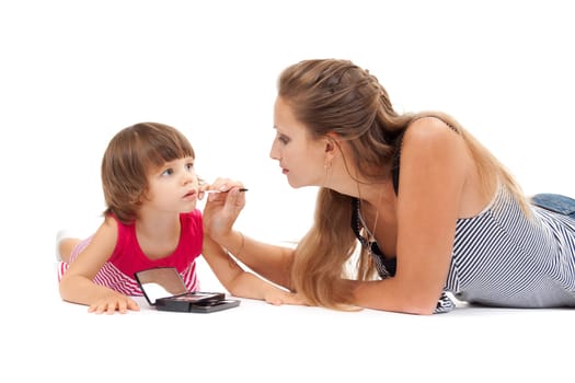 Young mother paints lipstick little daughter in the studio on a white background
