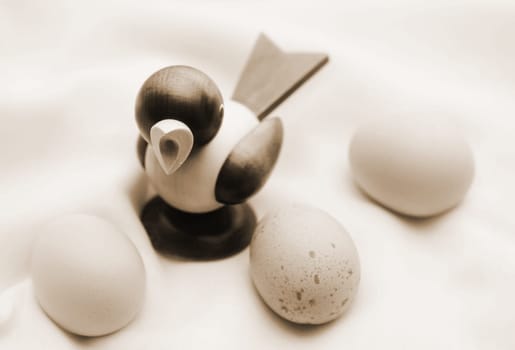 The photograph of three chicken eggs on a cloth with a wooden figure (Piepmatz).