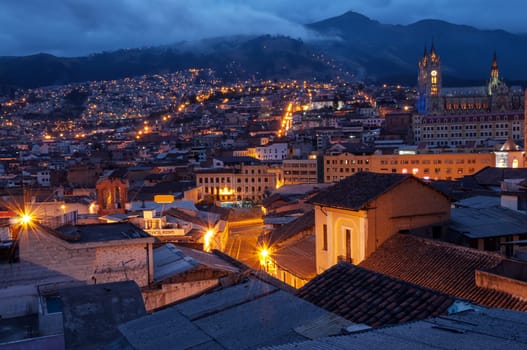 Quito, Ecuador old town and basilica at night with mountains in the background