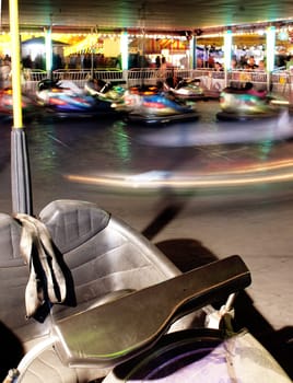 A Vehicle Stands Unused in a motion blurred photo of Bumper Cars at the Fair