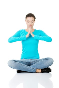 Portrait of young pretty student girl over white background meditating in lotus pose. She is relaxed and concentrated