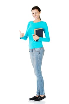 Attractive young student woman with book gesturing OK, isolated on white