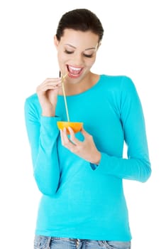 Attractive smiling young woman drinking orange juice straight from fruit