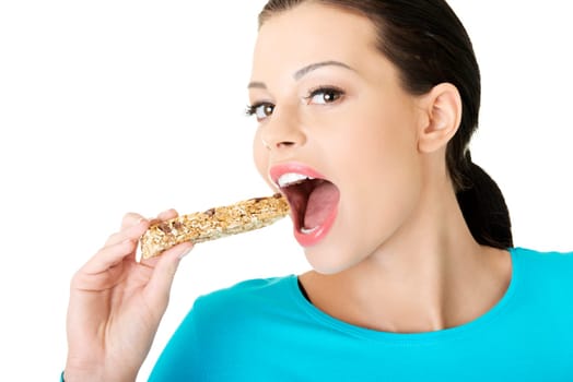 Young woman eating Cereal candy bar, isolated on white