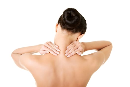 Naked young woman holding hands on neck in back pain. Brunette standing exposing back, shoulder, neck and hands. Isolated on the white background.