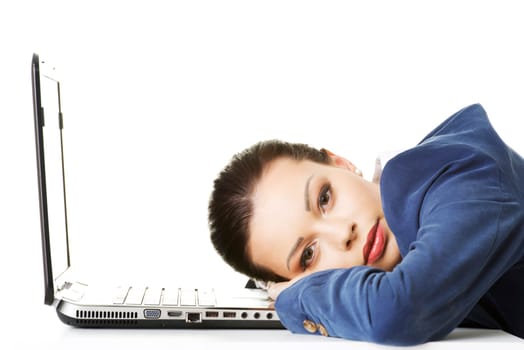 Beautiful bored and tired businesswoman lying down on desk next her laptop