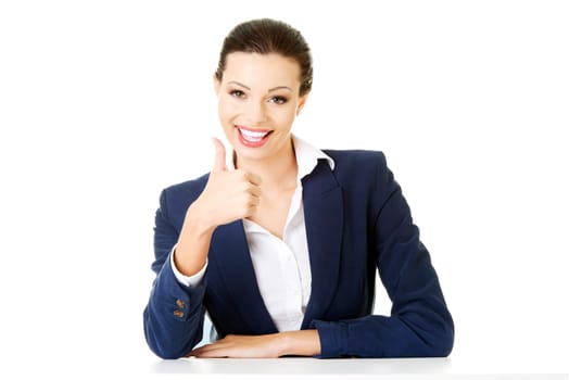 Young woman at the desk gesturing OK , isolated on white