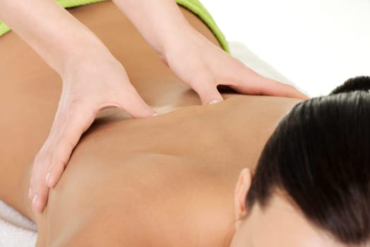 Pretty young woman relaxing beeing massaged in spa saloon