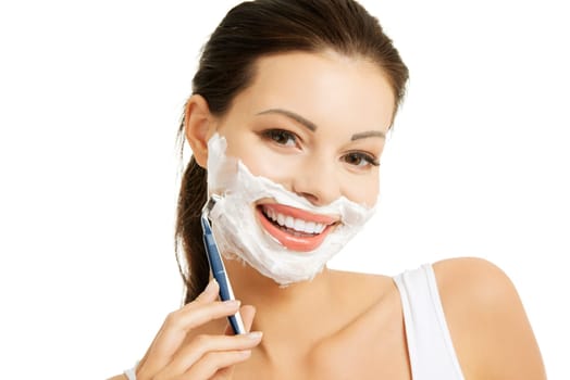 Beautiful young woman shaving her face with a razor