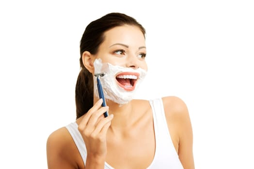Beautiful young woman shaving her face with a razor