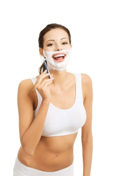Beautiful young woman shaving her face with a razor