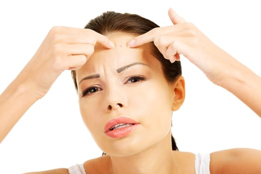 Young woman with pimple on her face. Trying to squeeze it. Isolated on white background.
