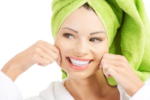 Beautiful woman with a towel on her head holding her cheeks and looking on side, isolated on white