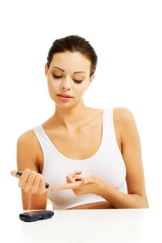 Diabetes patient measuring glucose level blood test using ultra mini glucometer and small drop of blood from finger isolated on a white background