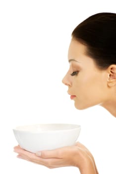 Beautiful young woman holding bowl and smells