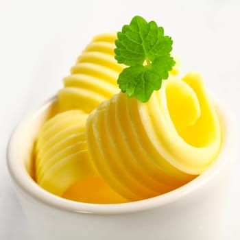 Closeup view with shallow dof of slices of rolled golden butter ffor a catered event or restaurant in a small ceramic dish garnished with mint