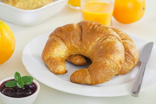 Freshly baked crisp golden croissants with delicious whole berry jam and orange juice for a healthy breakfast