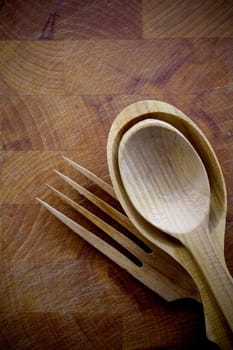 Set of three handcrafted wooden salad servers lying on a wood board with texture and grain