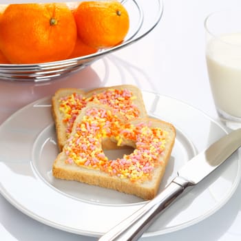 Tasty breakfast made of slices of bread with candies, oranges and milk