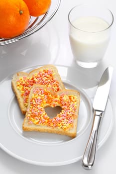 Tasty elegant breakfast made of slices of bread with candies, oranges and milk