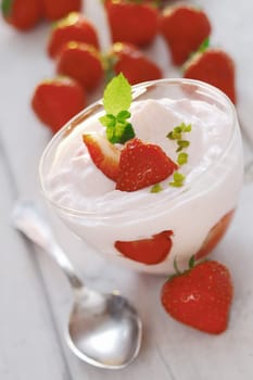 Ripe red juicy strawberries and fresh yoghurt or whipped cream in a glass bowl for a refreshing dairy dessert