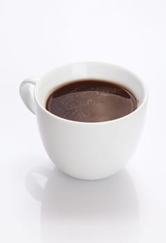 Plain white china cup of hot fresh strong black coffee on a white background with reflection
