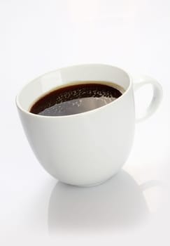 Studio shot of a white china cup, filled with rich black coffee, on white background with reflection