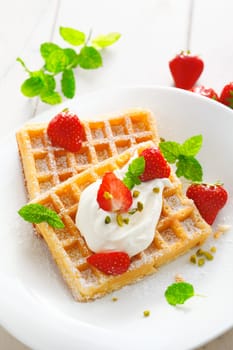 Crisp golden waffles, strawberries and cream garnished with fresh mint and sprinkled with sugar for a delicious summer dessert