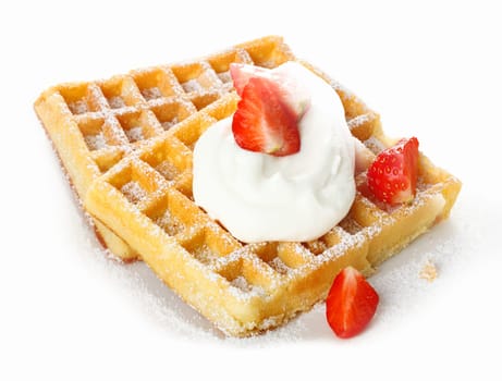 Fresh ripe red strawberries and whipped cream on a crisp golden waffle sprinkled with sugar for a refreshing dessert