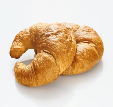 Freshly baked crisp flaky golden croissants in the traditional crescent shape on a white studio background