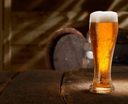 Closeup of a glass of fresh foamy beer on a table in a vintage beer cellar