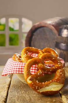 Crisp salty golden-brown pretzels served as a savoury snack in a pub or restaurant with an old wine barrel visible behind