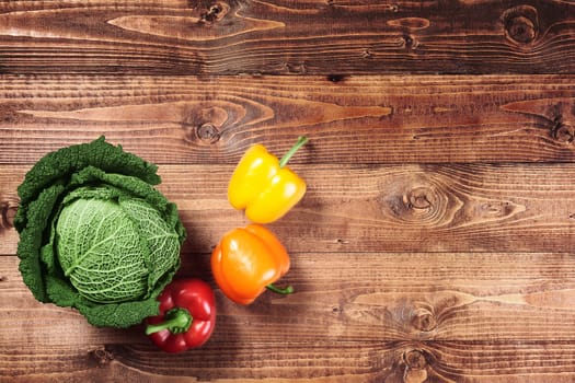 Cabbage and red and yellow peppers on wood