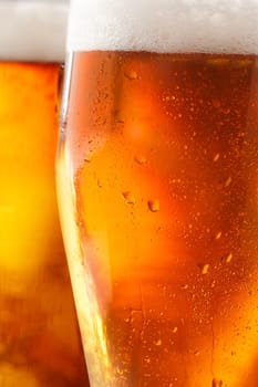 Cropped closeup of a glass of cold beer with a frothy head and water droplets from condensation beading the outside of the glass