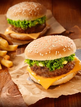 Two hamburgers and french fries on brown paper