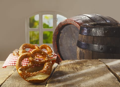 Traditional crisp golden-brown knot shaped pretzels on a rustic wooden table in front of an old oak wine or beer barrel at a country restaurant or pub
