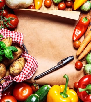 Garden fresh vegetables and blank brown paper and pen
