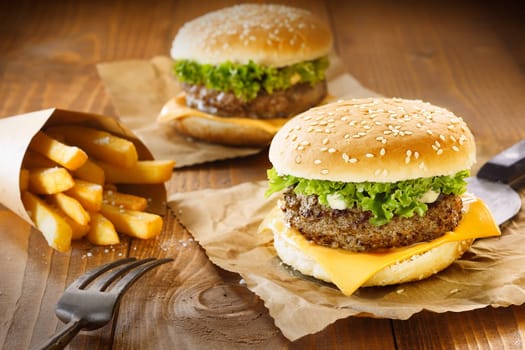 Two hamburger and fries on brown paper and wooden table