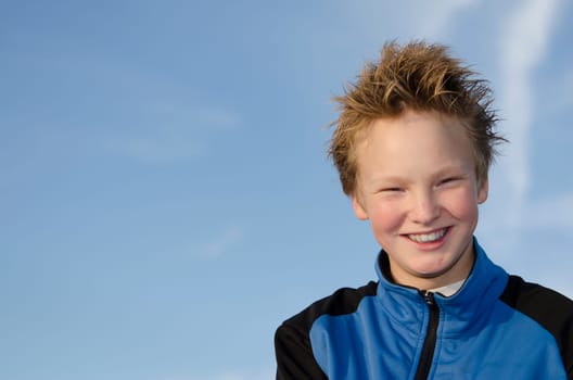 Happy teenager with spiky hair against blue sky background