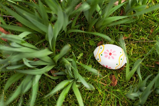 Painted Easter egg hidden in the grass and bulbs.