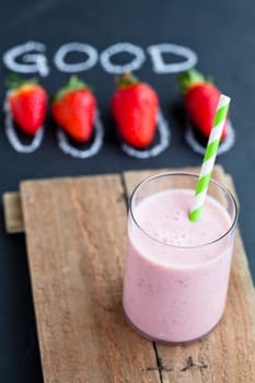 Strawberry smoothie with striped straw and whole strawberries