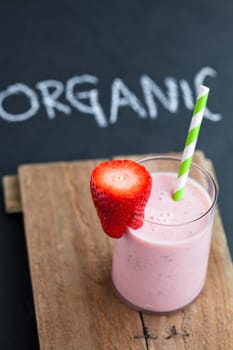 Strawberry smoothie with striped straw and sliced strawberry