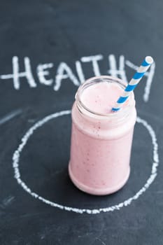 Strawberry smoothie with striped straw with text on dark background