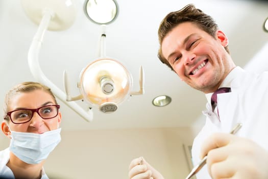 Scary dentist with dental assistant during a treatment from the patient's point of view