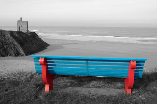 ballybunion bench in winter with view of beach castle and cliffs in black and white except bench